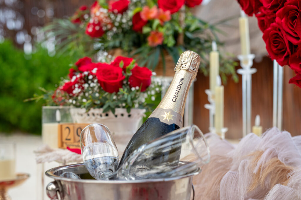 A bottle of Chandon champagne in an ice bucket with glasses, surrounded by red roses and candles.