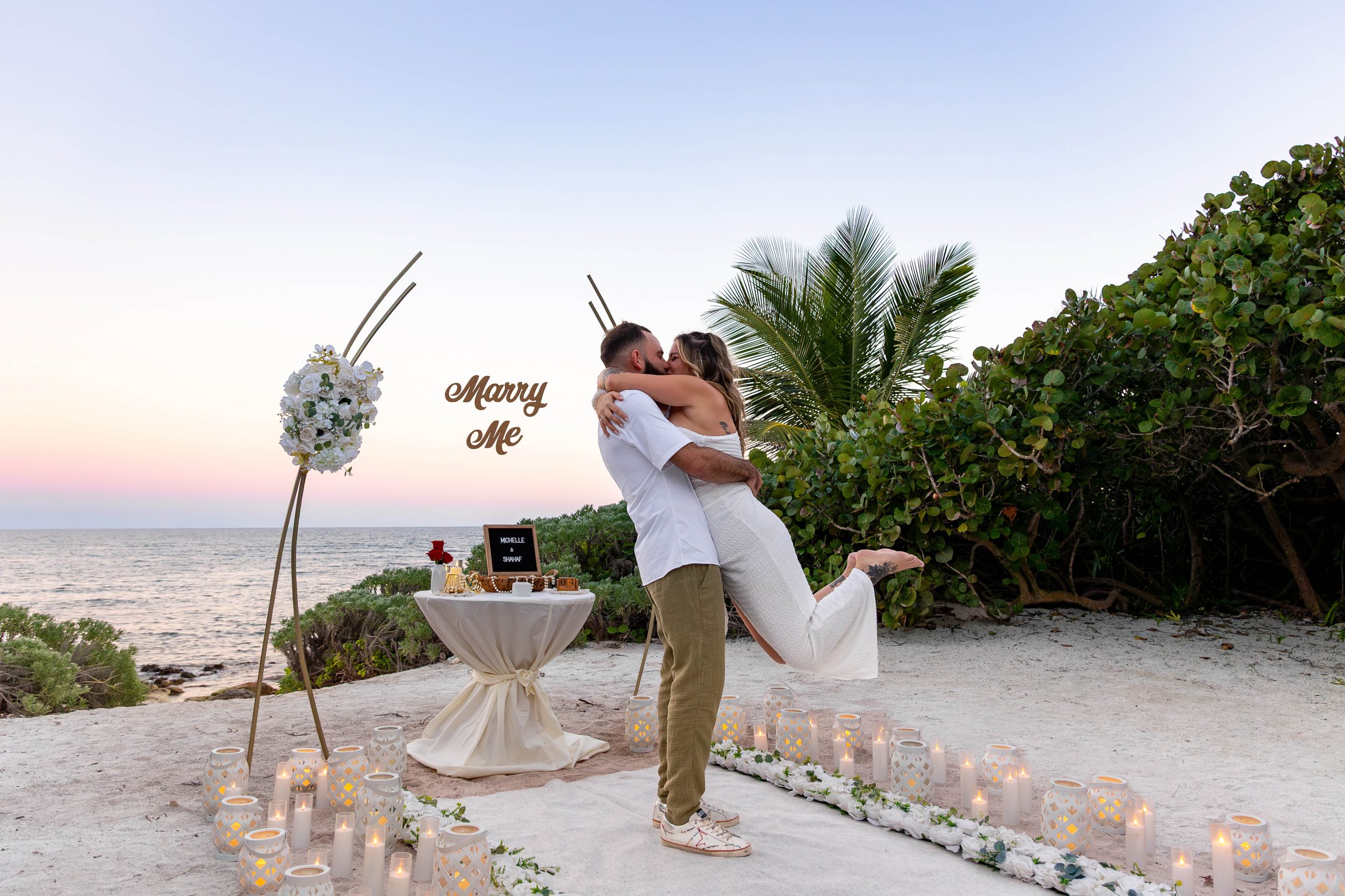 Luxury sunset beach proposal at Akumal private beach with floral arch, candles, and ocean view in Riviera Maya.
