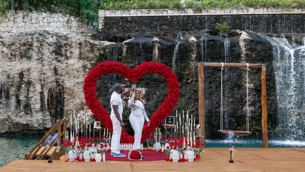 Luxury red heart proposal at a private cenote with fresh red roses, candlelight, and waterfall backdrop in Riviera Maya