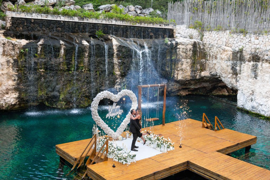 Luxury white heart arch proposal at a private cenote in Riviera Maya with candles and fresh flowers