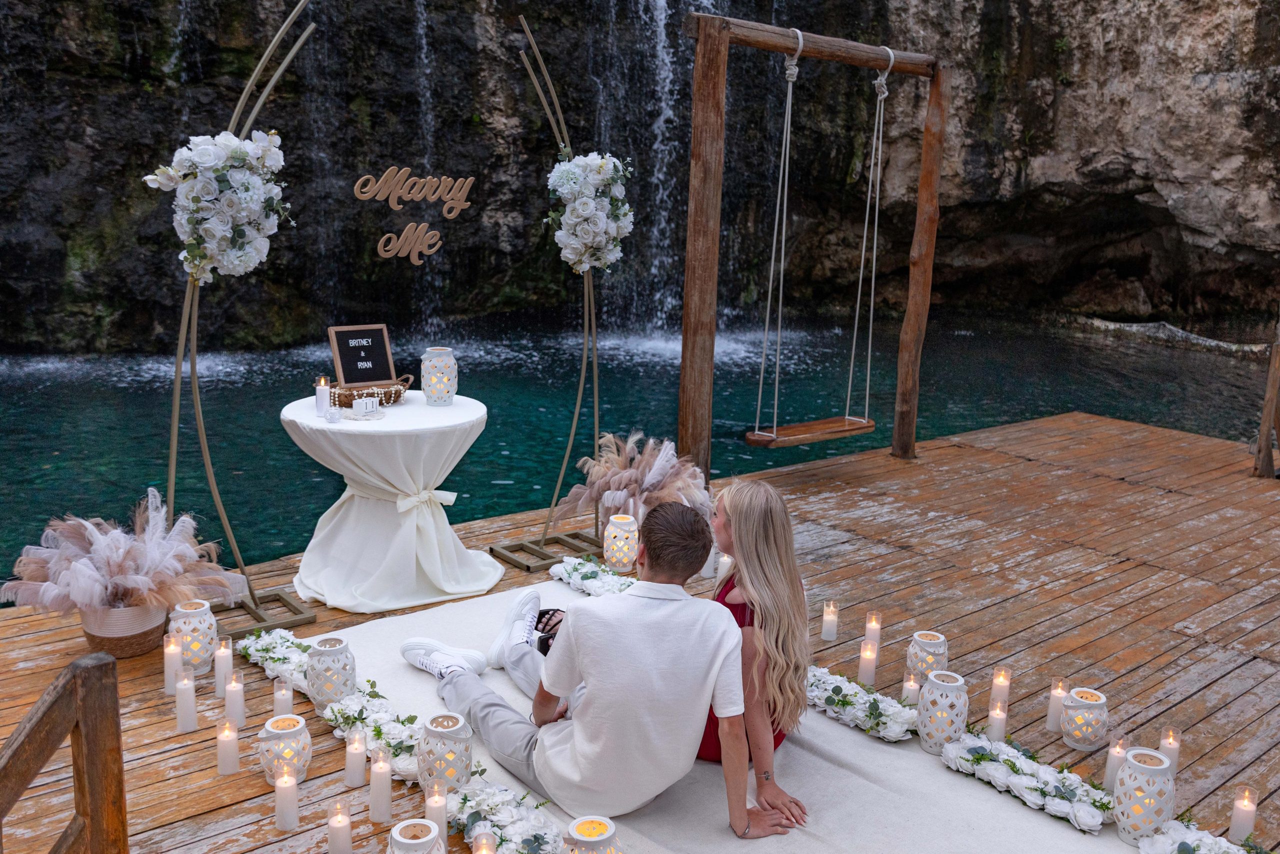 Luxury cenote proposal in Riviera Maya featuring a fresh floral setup and engagement ring reveal beside a natural waterfall