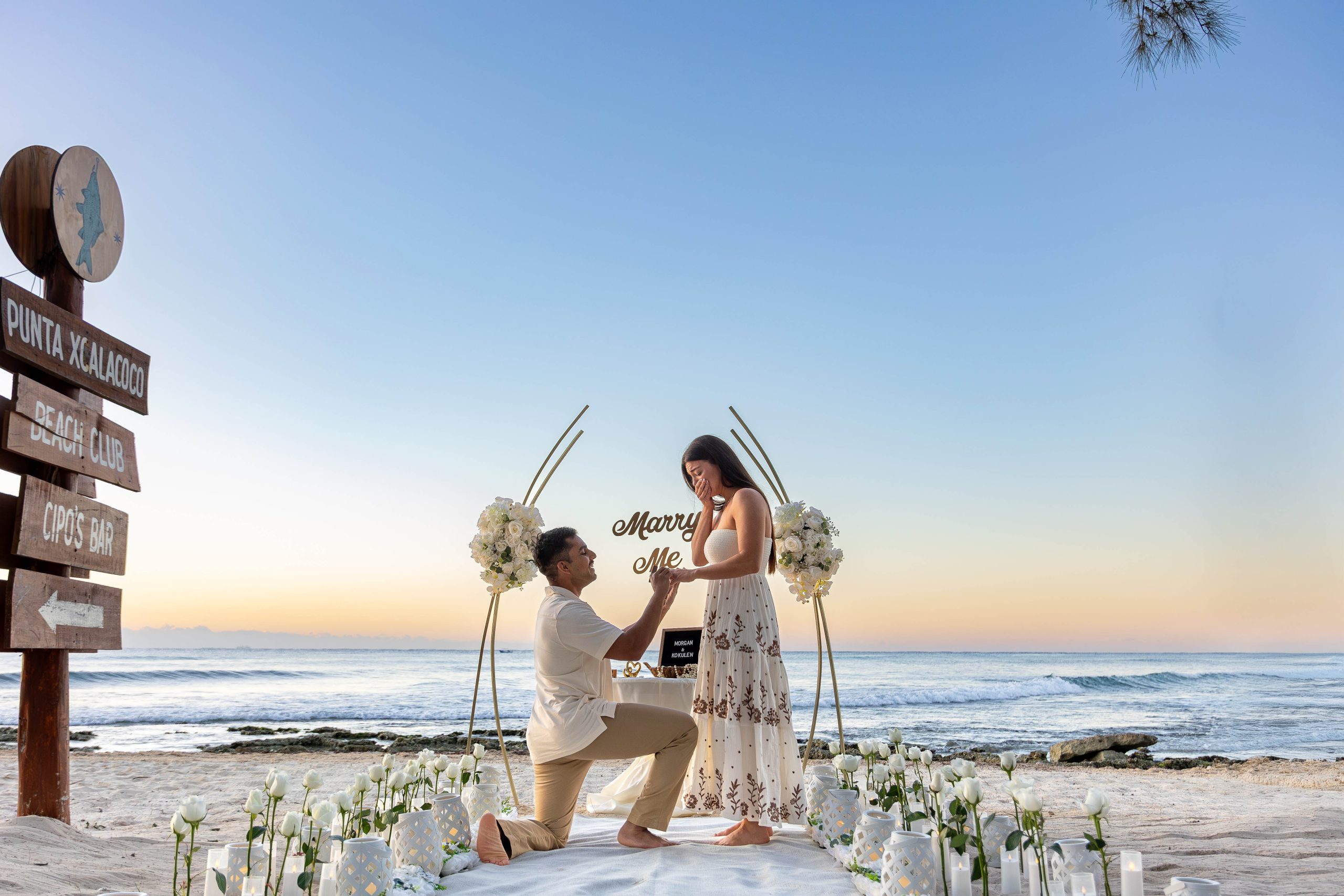 Sunrise beach proposal at Xcalacoco Beach Club in Playa del Carmen with floral arch and ocean backdrop.