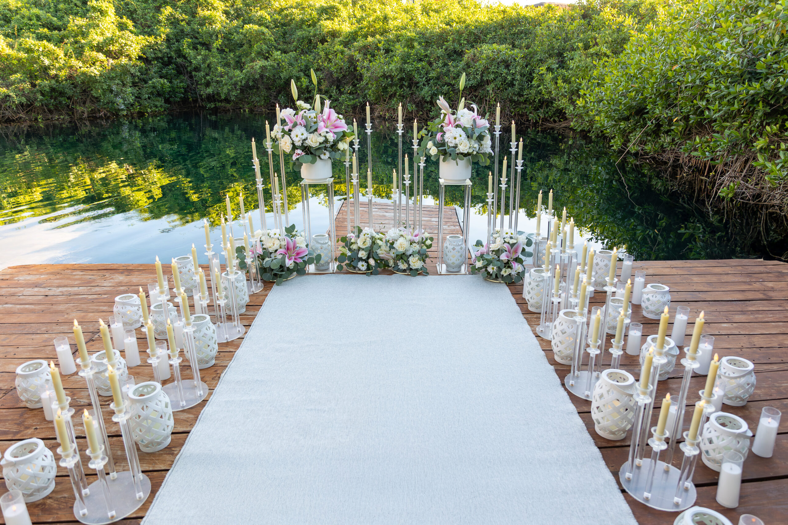 Luxury cenote proposal setup in Riviera Maya Mexico with white floral arrangements, candles, and elegant wooden deck overlooking turquoise water