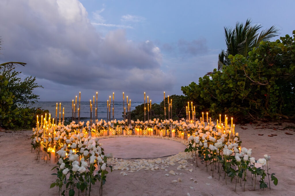 Luxury beach proposal setup with hundreds of fresh white roses and candlelight in Akumal Riviera Maya