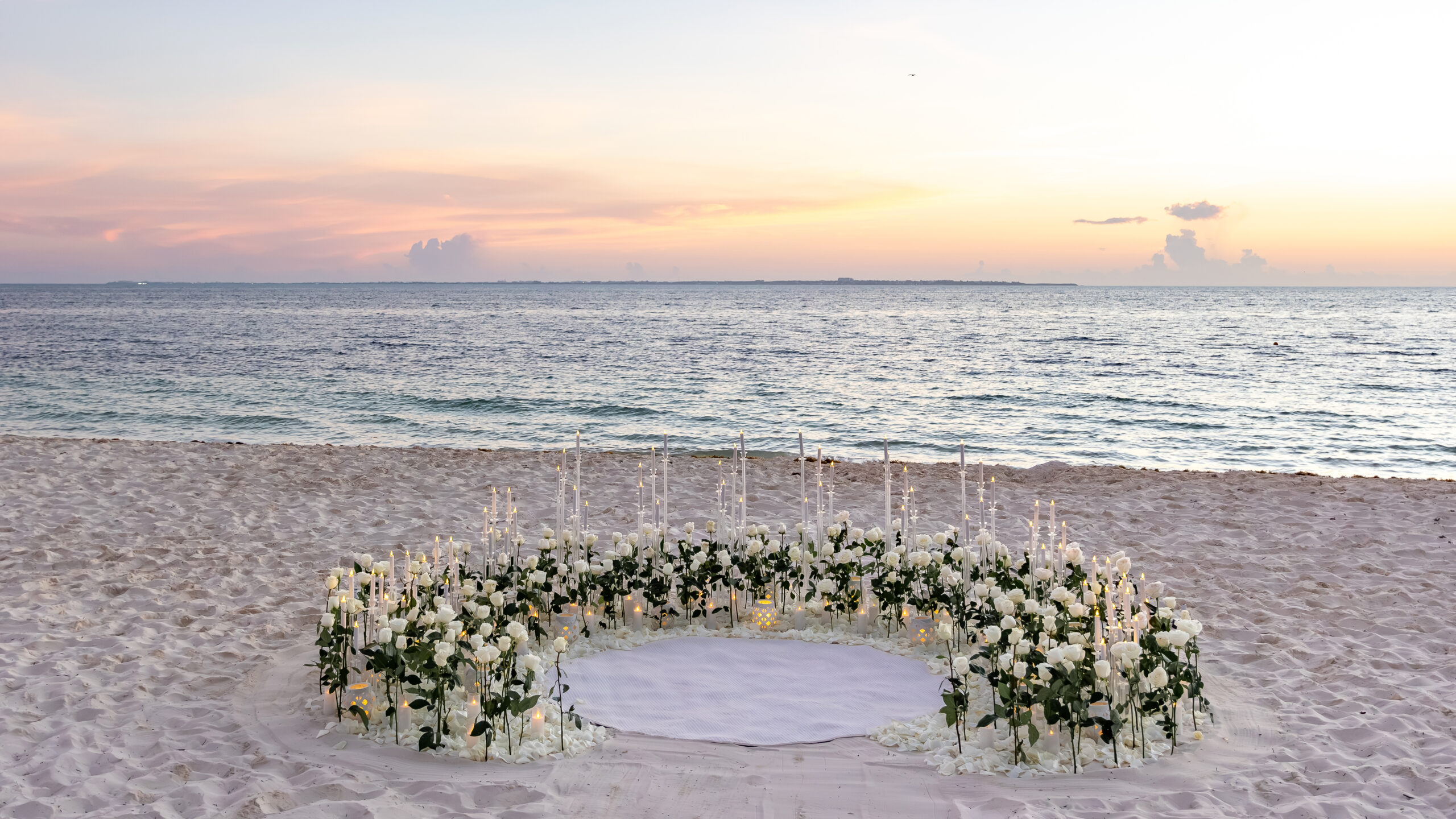 Sunrise proposal setup with white roses on the beach at RIU Caribe Cancun