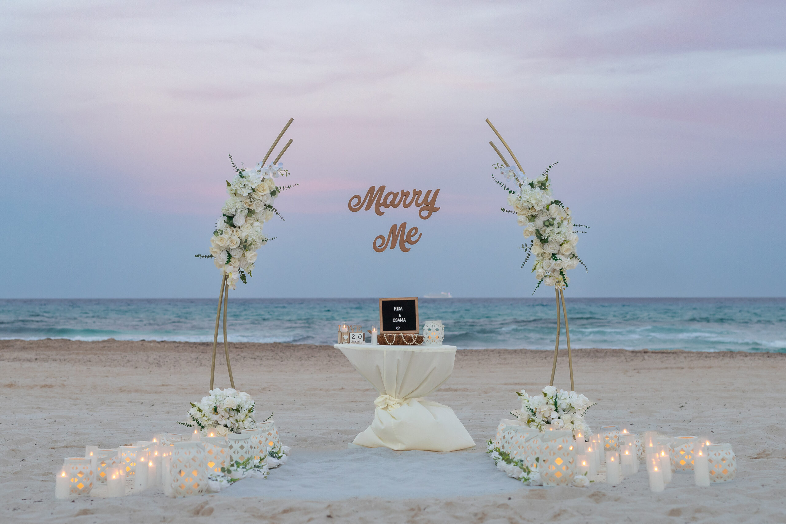 Intimate white-floral beach proposal at sunset